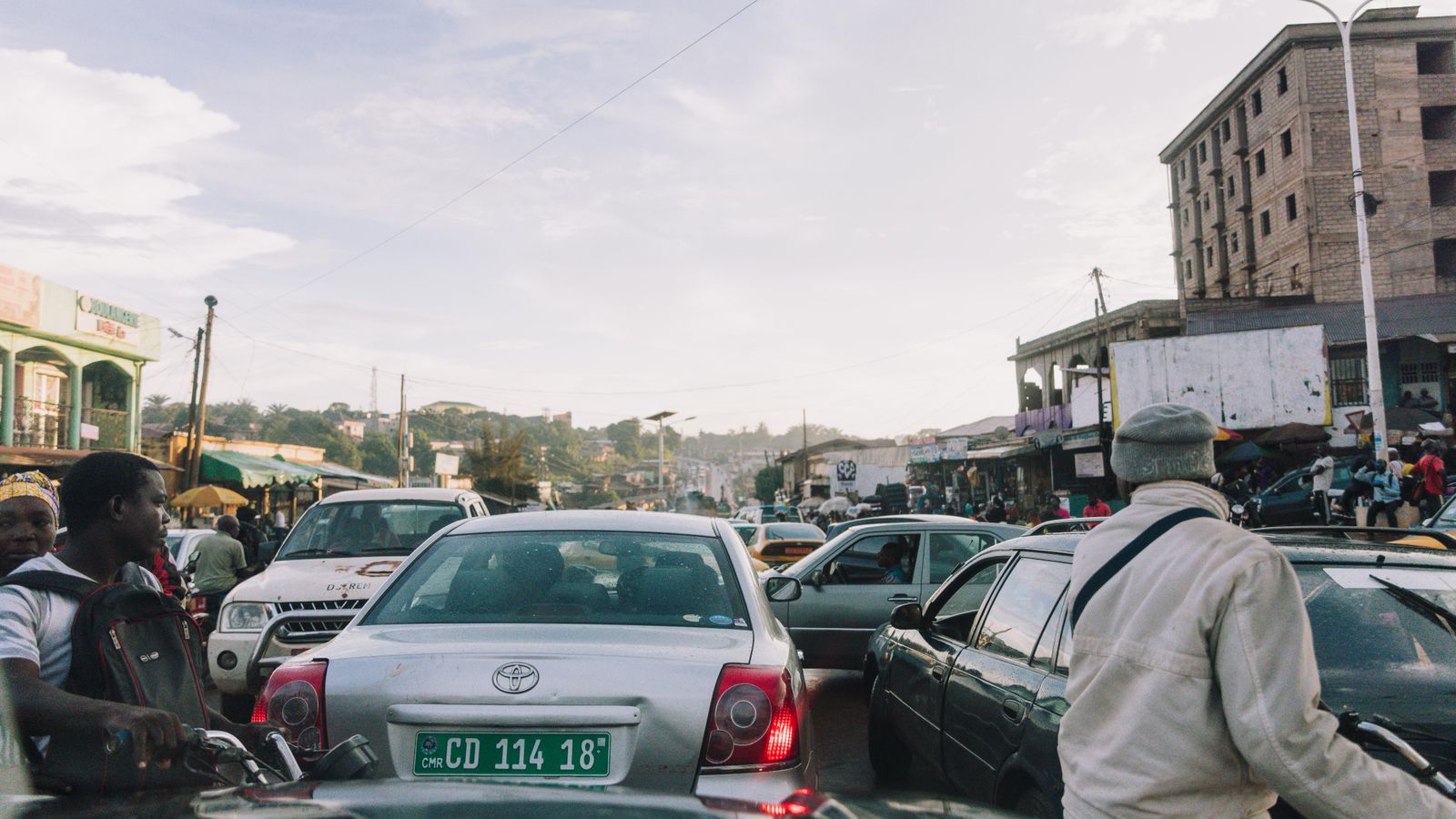 Gridlocked traffic in Yaoundé, a man in a white jacket walking between the cars